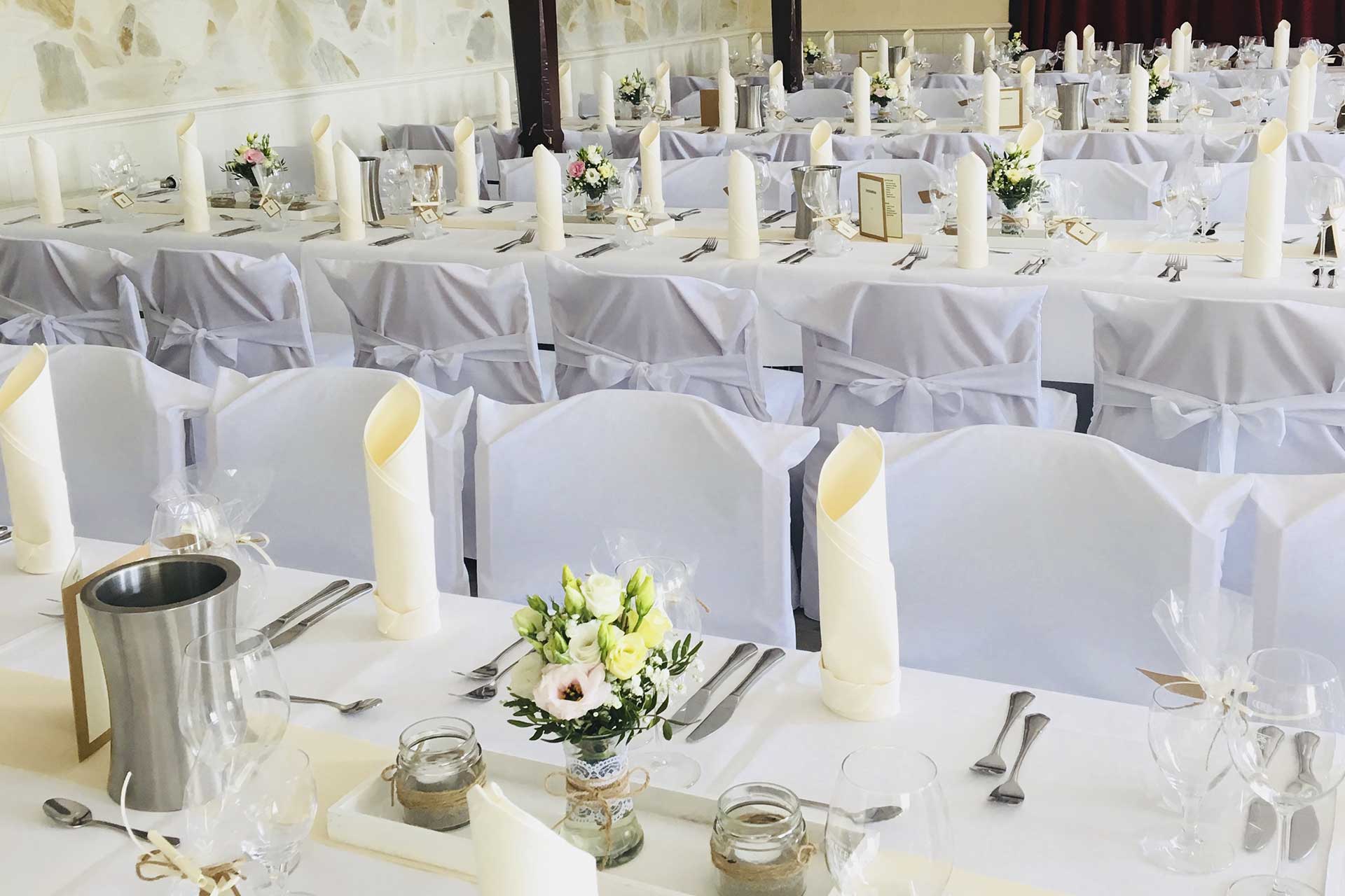 Saal für eine Hochzeitsfeier eingedeckt mit weißen Stuhlhussen
